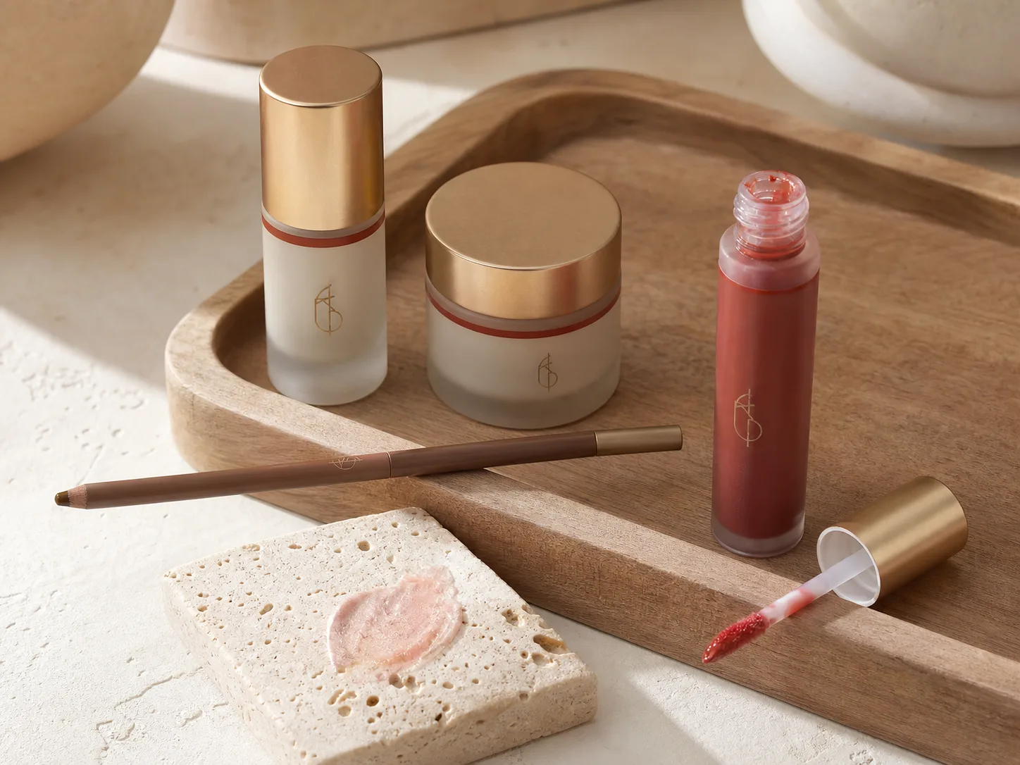 Rosy lip tint, soft brown brow pencil, pearly cream swatch, and premium makeup containers on a wooden tray